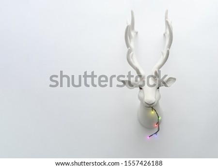 Santa deer decoration with Christmas tree lights. Creative Holiday concept. Reindeer minimal background.