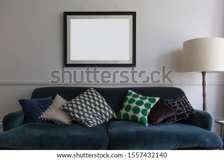 Empty picture frame hanging above a blue sofa in a living room