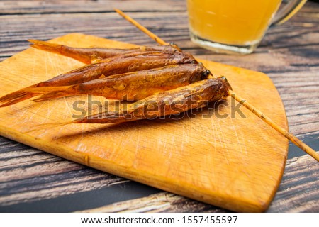 Dried mullet on a wooden Board with a mug of beer on the table. Fish and seafood cuisine. Tasty snack.
