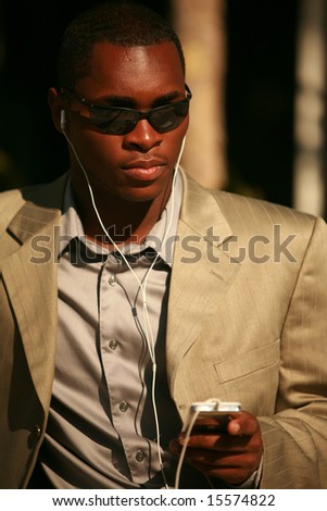 a well dressed Male Model listens to his personal digital music player