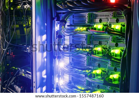 Racks with server equipment are in the dark room of the data center. Colorful indication of the network interests of the Internet router. Information Technology Concept. Royalty-Free Stock Photo #1557487160