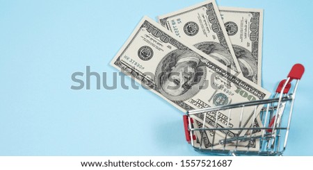 US dollars in shopping cart over blu background ,Dollar bill collect on shopping cart.Concept of money. Copy spase, spase for text.