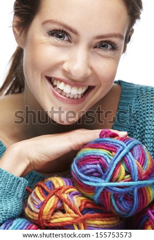 Beautiful woman sitting with yarn rolls on a white background