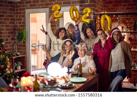 Beautiful group of women smiling happy and confident. Posing around christmas tree holding 2020 ballons at home