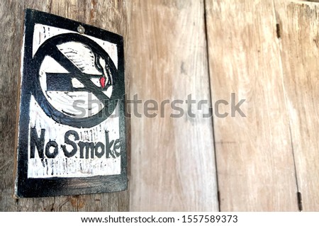 No smoking black and white sign on old brown wooden wall.
