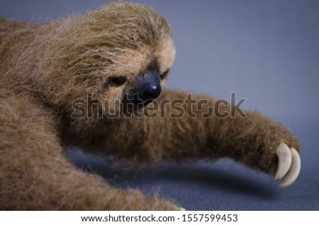 Sloth crawling side view handmade toy from natural sheep wool studio photo on a gray background close-up
