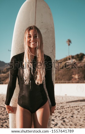 young woman standing with surfboard at Malibu beach