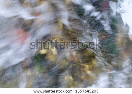 slow shutter speed, to show water flowing over rocks with ice formations. Flowing Water. Selective focus. Abstract background