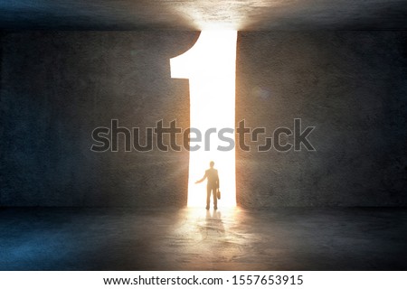 Man looking up at glowing door in number shape Royalty-Free Stock Photo #1557653915