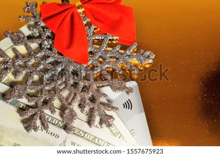 Christmas or New Year card. Silver snowflake decorated with a red bow with banknotes and a bank card on a gold background