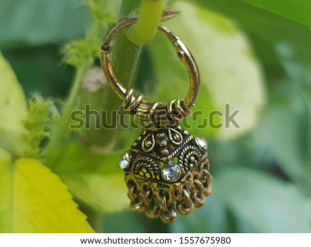 gold metal earring on green background