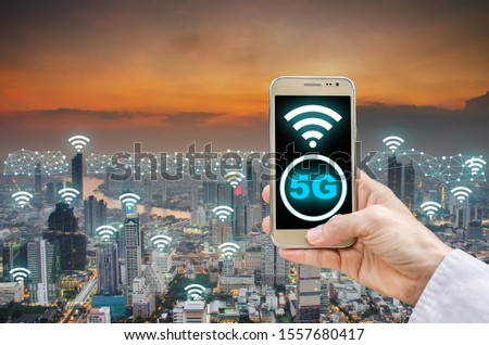 Mobile network connection technology concept, 5G network digital mobile phone and wifi icon on city background, businessman holding phone and icon 5g on city background.
