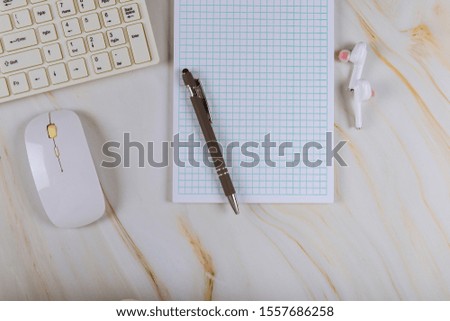 Workplace with notepad, wireless headphones and computer keyboard on mouse in marble background