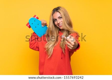 Young skater woman over isolated yellow background