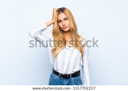 Young blonde woman over isolated blue background with an expression of frustration and not understanding