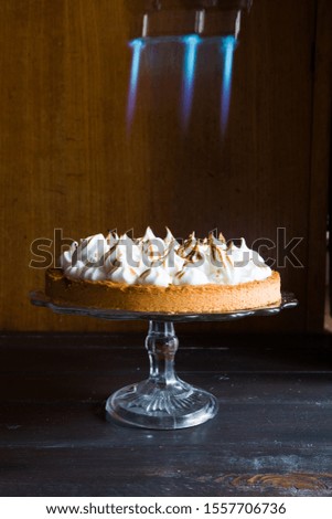 Lemon tart with french meringue caramelized on top, on a rustic table, french meringue caramelized with a food torch.