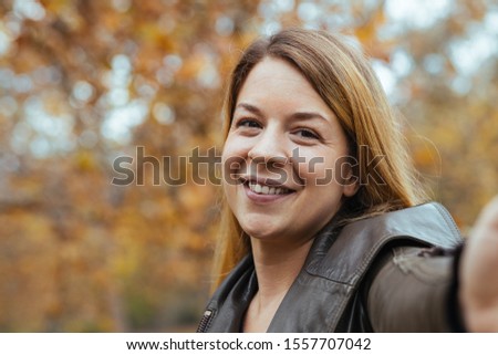 Young woman taking a selfie in the park in autumn
