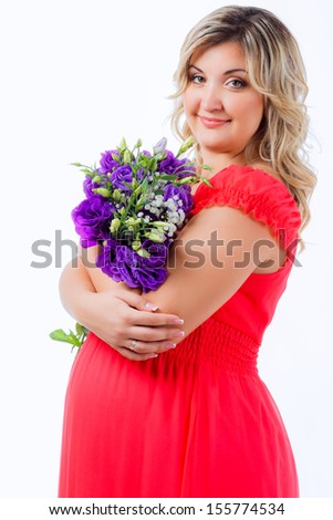 beautiful pregnant girl in a bright dress with flowers. close-up. looking at the camera