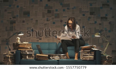 Stressed businesswoman working on the sofa late at night, she is overloaded with work, deadlines and overtime work concept Royalty-Free Stock Photo #1557750779