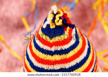 Carnival abstract colors background. Jester hat for Carnival and Mardi Gras. With streamers background. Colored Cap. Knitted Wool Hat