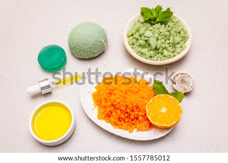 Healthy self-care. Minimalistic organic lifestyle. Comfort and natural pharmacy. Set of sea salt, herbal oil, mandarin and fresh mint leaves. Bowls, stone concrete background, close up