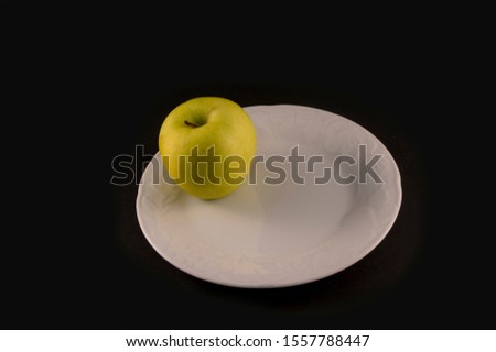 minimalist photography with golden apple on white plate isolated on black background