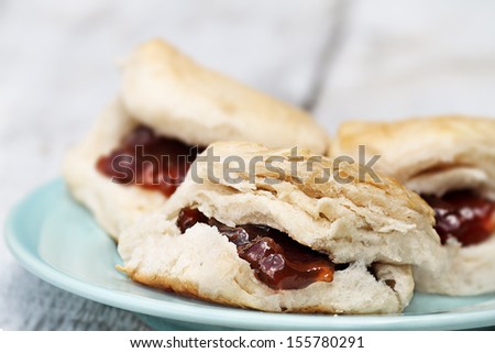 Closeup of freshly baked scones at the breakfast table with strawberry jam. Extreme shallow depth of field with selective focus.