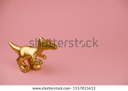 golden dinosaur statuette on pastel pink background with copy space trendy minimal art card 