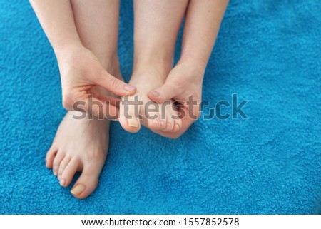 Foot massage.
A woman performs a foot massage during a care treatment. Bare feet on a blue towel. composition, real picture without retouching