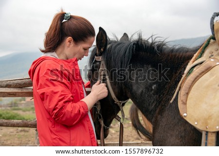 A woman of forty years, gently stroking the horse's muzzle in the background of a misty mountain landscape.