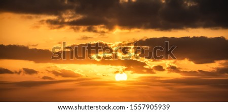 Shining sun and dark clouds at sunset