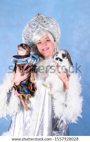 Animator woman in the Studio on a blue background in a snow maiden costume in a crown with a dog and a lop eared rabbit