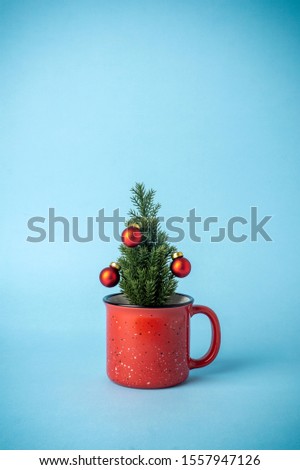 Christmas tree with decorations in a cup on a blue background. Christmas holiday drinks.