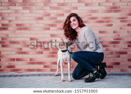 young woman and her dog at the city. standing by a brick wall