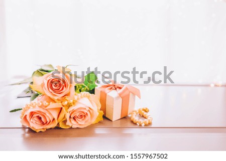Rose fresh flowers bouquet on gray table by the window with gift box, toned