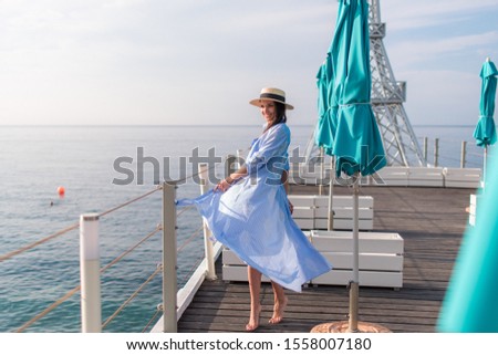 
Beautiful slim woman in a swimsuit and pareo posing on a pier near the sea