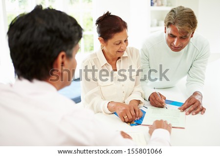 Senior Indian Couple Meeting With Financial Advisor At Home