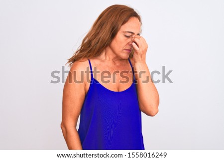Middle age mature woman standing over white isolated background tired rubbing nose and eyes feeling fatigue and headache. Stress and frustration concept.