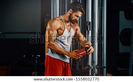 Muscular Men Drinks Protein Drink, Energy Drink in the Gym Royalty-Free Stock Photo #1558032770