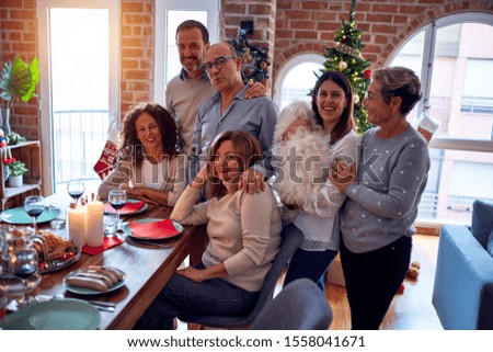 Family and friends dining at home celebrating christmas eve with traditional food and decoration, taking picture all together