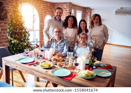 Family and friends dining at home celebrating christmas eve with traditional food and decoration, taking picture all together