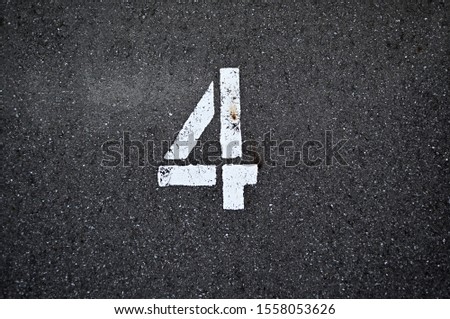 A parking number "four" on asphalt.