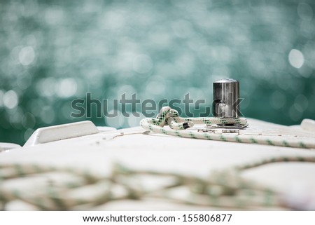 White mooring rope tied around steel anchor on boat or ship 