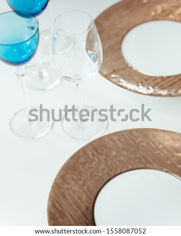 A high angle shot of a table setting with wine glasses and golden plates