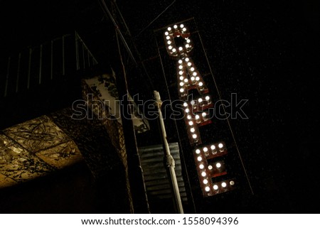 Street sign "cafe". Letters from light bulbs. Rainy weather