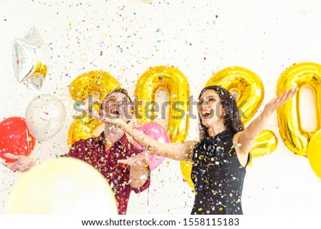 Happy new year 2020 concept. Portrait photo of happy people with 2020 texts balloons and party poppers on white background.