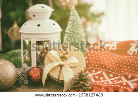 Christmas background decoration with white lantern, pine leaves, pine cones, balls and luxury golden gift box on wood table with copy space. Bokeh Christmas tree wallpaper for xmas celebration.