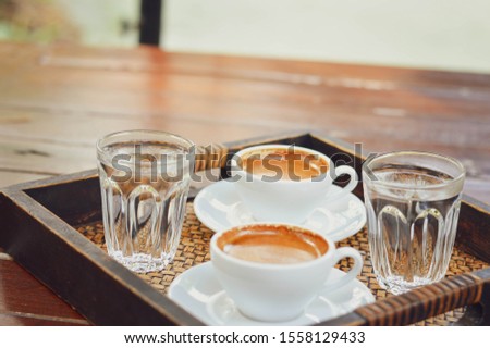 Two cups of coffee placed on a wooden tray selective focus.