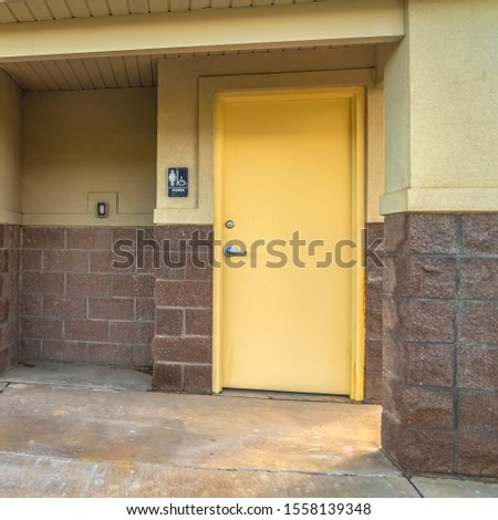 Square Exterior of a public restroom with men women and handicaped signs on the wall