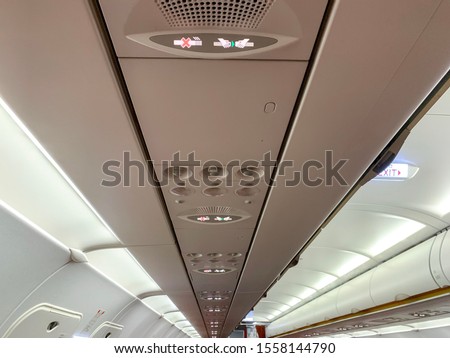 Air conditioning and lighting control panel at overhead compartment of commercial airplane cabin.
Fasten seat belt and no smoking signs on a plane.